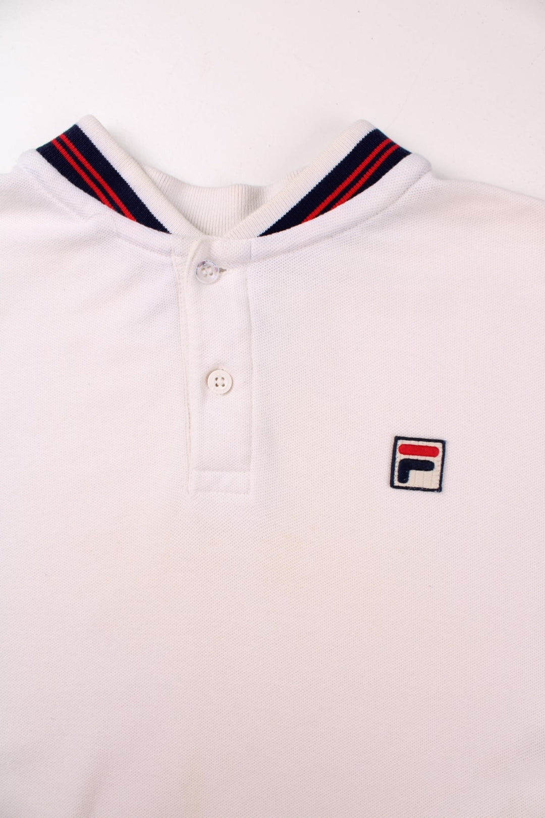 Vintage Fila white line polo shirt in white with two buttons at the neck, blue and red stripe details at the collar, and an F logo on the chest.