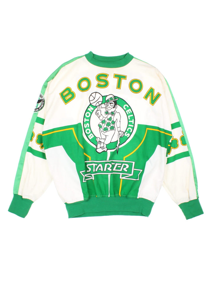 Vintage 1990s Starter Boston Celtics NBA Sweatshirt in a white and green colourway. The sweatshirt has a large graphic on the front, and back with a satin stripe down the arms and an embroidered starter patch on the sleeve. Features elasticated cuffs and hem and also has two side pockets. 