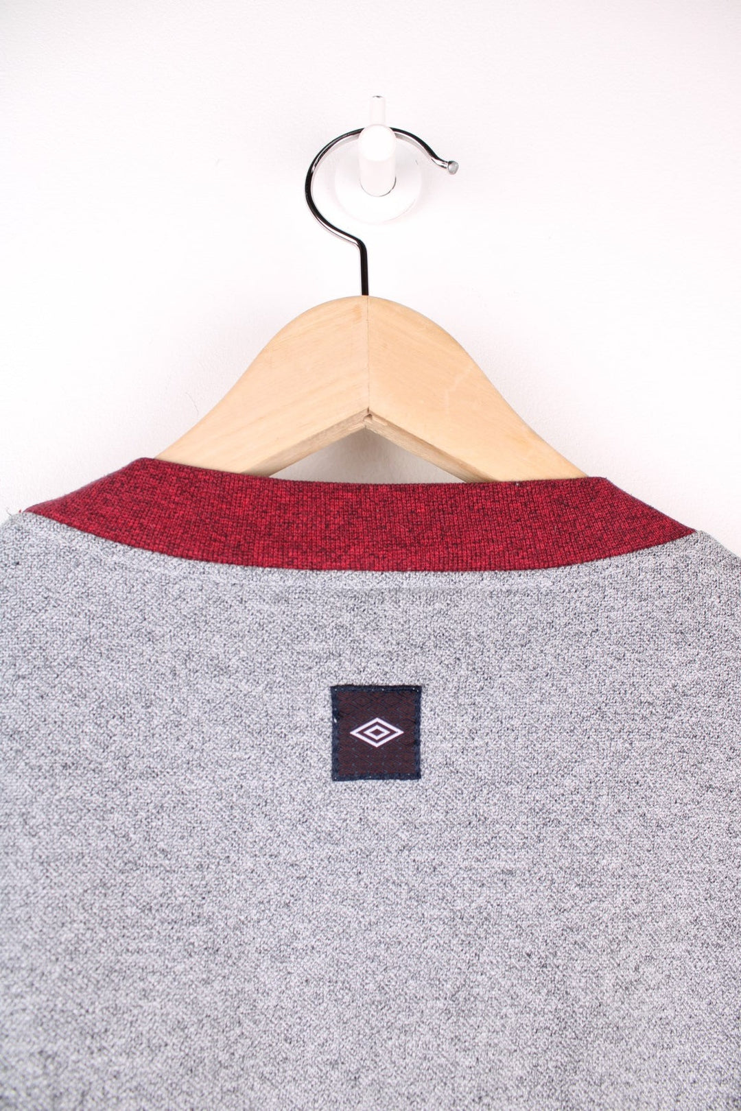 Umbro sweatshirt in grey with sleeves, collar, and embroidered logo in red, a black logo patch on the back, and one breast pocket. 