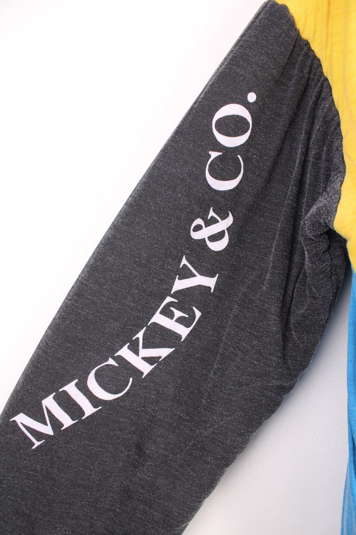 80s/90s Disney reversible lined sweatshirt with one red, yellow, and blue colourblocking side featuring a large Mickey Mouse graphic and text reading 'Mickey and Co.', and one red side with a repeating Mickey head pattern. 