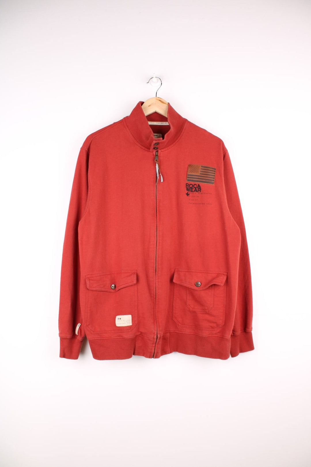  Y2K Rocawear Zip-through Sweatshirt in a red colourway with embroidered logo, button-close pockets and multiple patches stitched to the front and right sleeve.