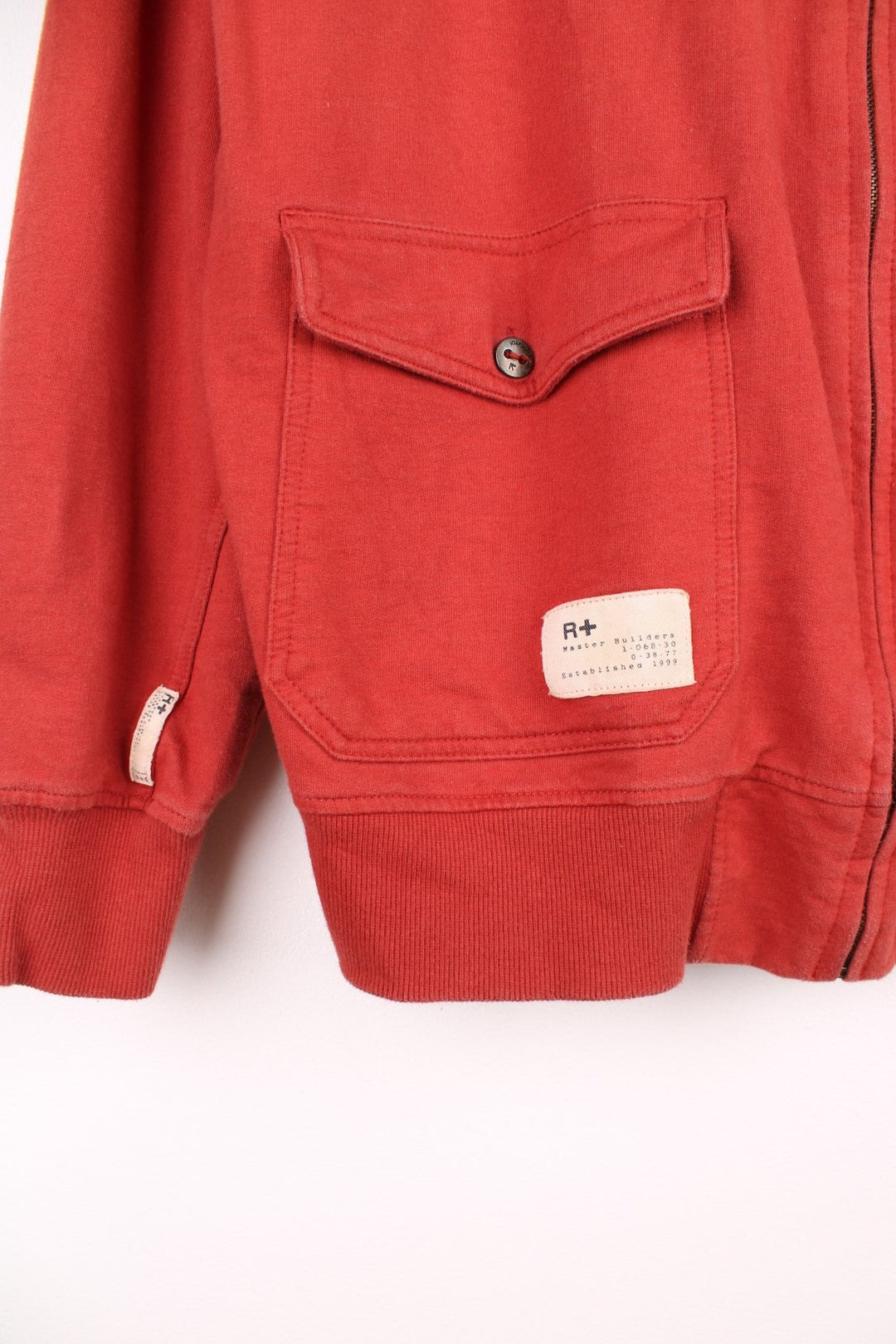  Y2K Rocawear Zip-through Sweatshirt in a red colourway with embroidered logo, button-close pockets and multiple patches stitched to the front and right sleeve.