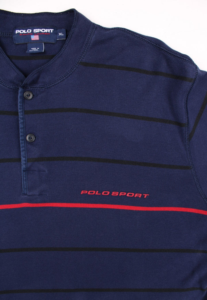 Vintage Ralph Lauren Polo Sport long sleeved Polo Shirt in a navy blue colourway with a small polo sport logo on the front, and red stripe running across the chest and arms. The shirt has a grandfather collar with two buttons to close. 