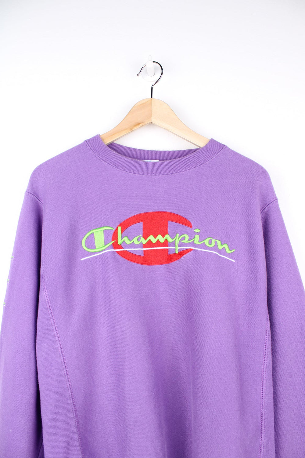 Purple Champion Reverse Weave sweatshirt with red and green embroidered logo across the chest and on the sleeve.