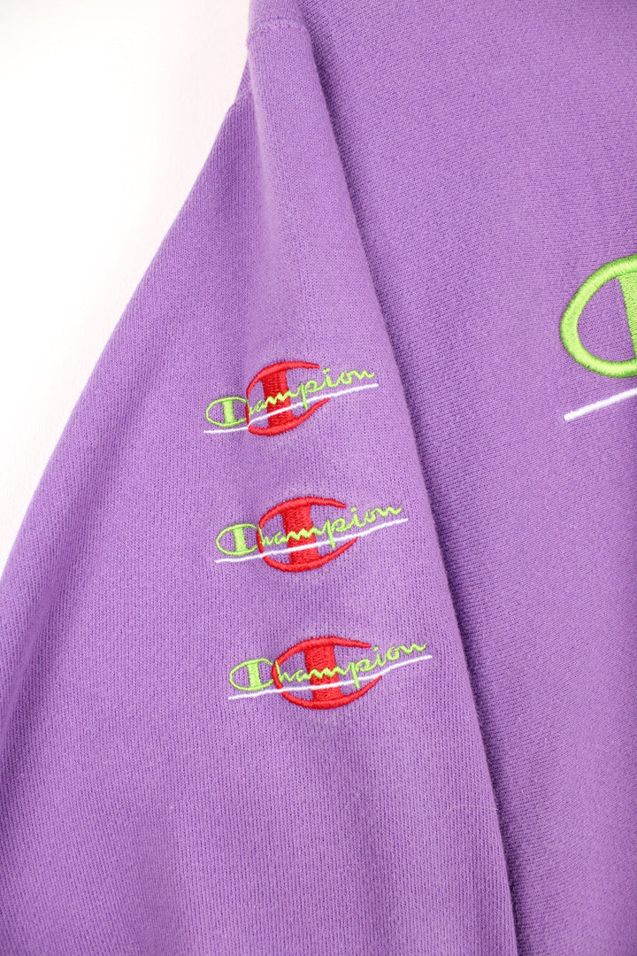 Purple Champion Reverse Weave sweatshirt with red and green embroidered logo across the chest and on the sleeve.