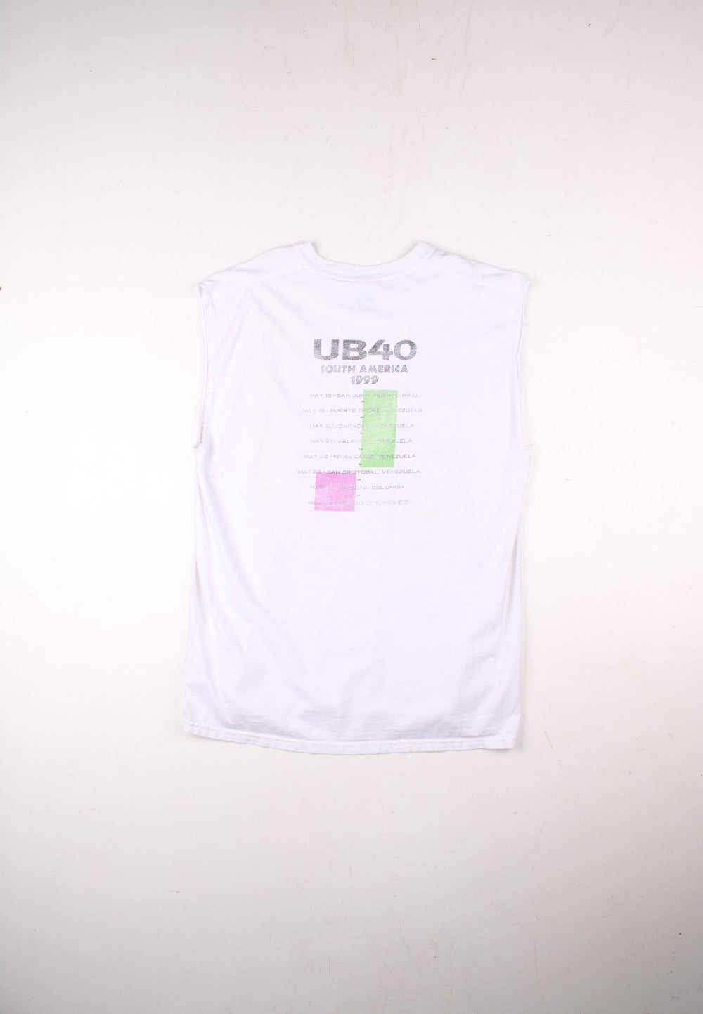 Vintage 1999 UB40 South America Tour Vest in a white colourway with the logo and art graphic printed on the front but is heavily faded, and on the back are the tour dates printed, this garment was a t-shirt which has had its sleeves removed.