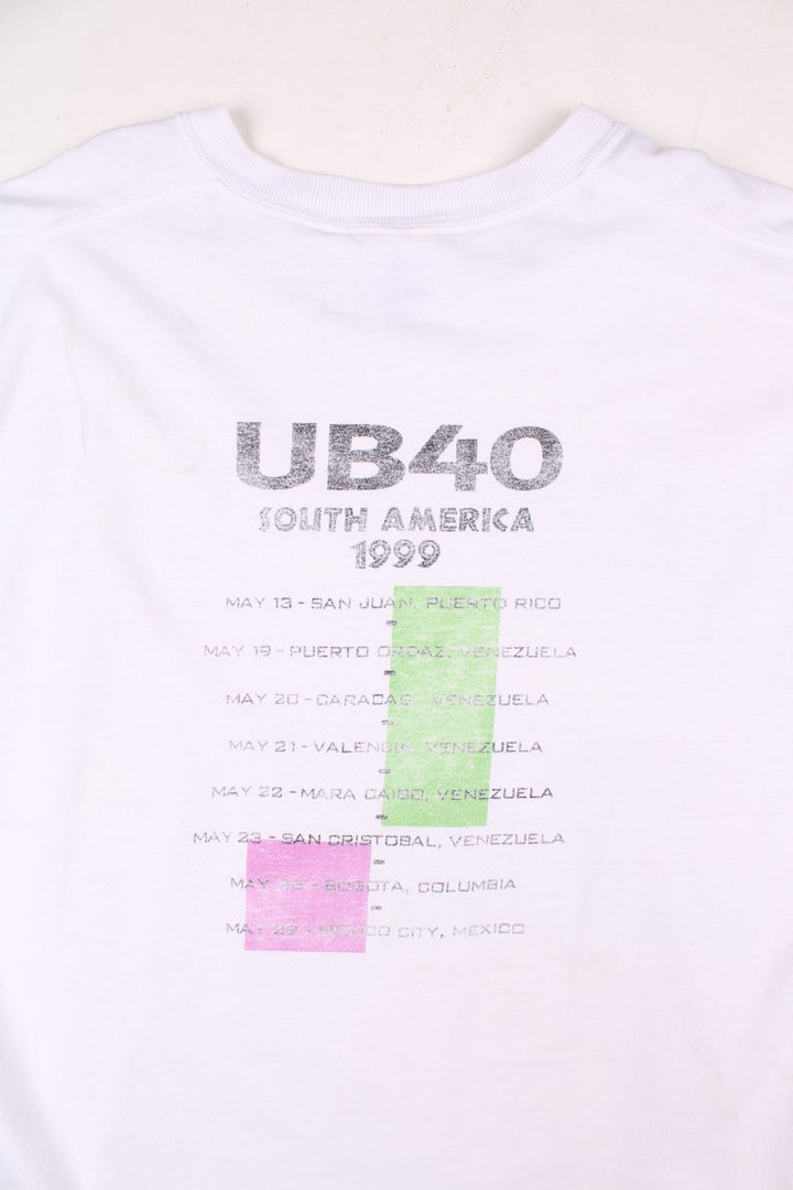 Vintage 1999 UB40 South America Tour Vest in a white colourway with the logo and art graphic printed on the front but is heavily faded, and on the back are the tour dates printed, this garment was a t-shirt which has had its sleeves removed.