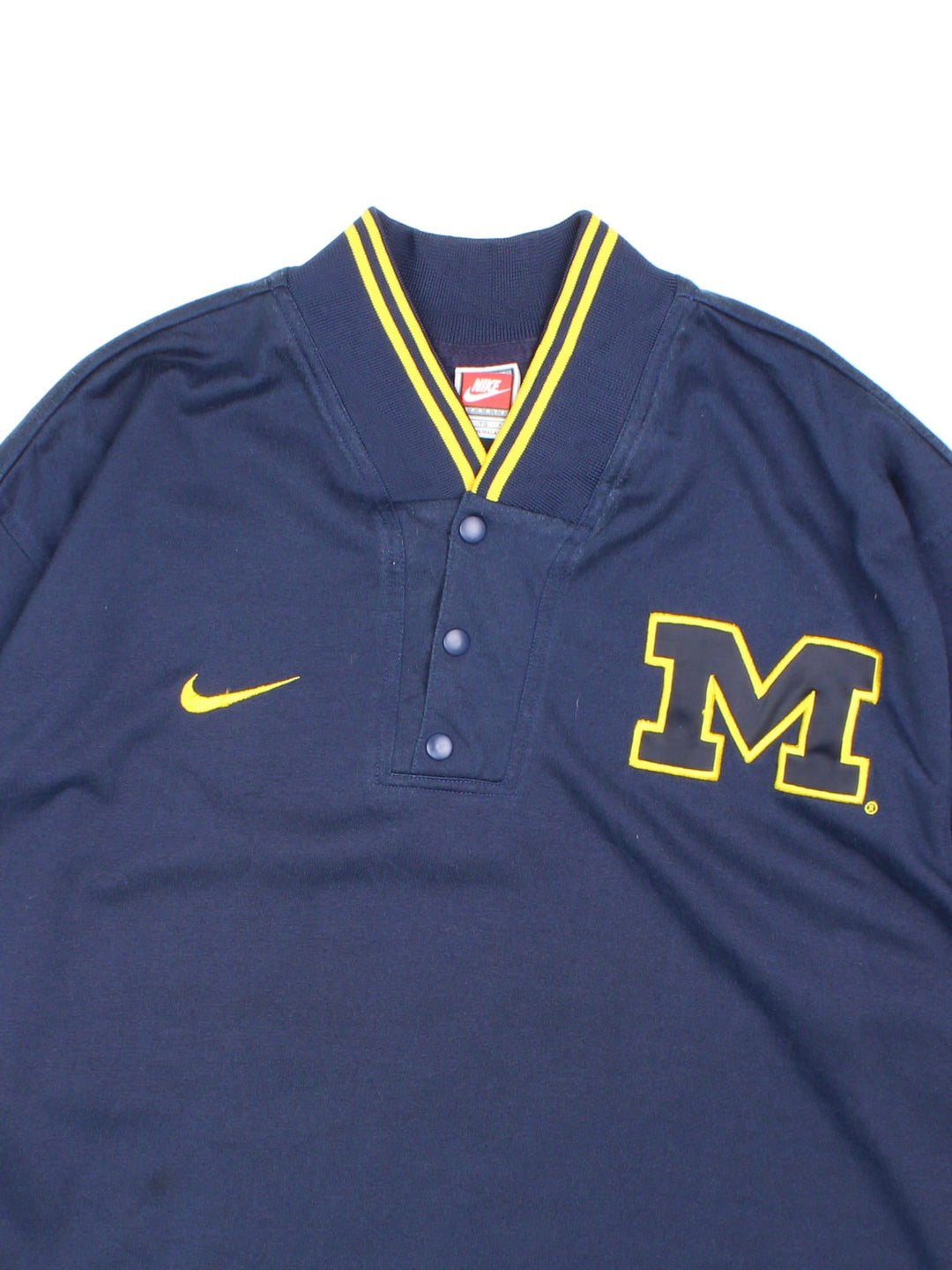 Michigan University Nike Wolverines Basketball Shooting Training Top in a navy blue and yellow colourway, button up collar and has the logos embroidered on the front.