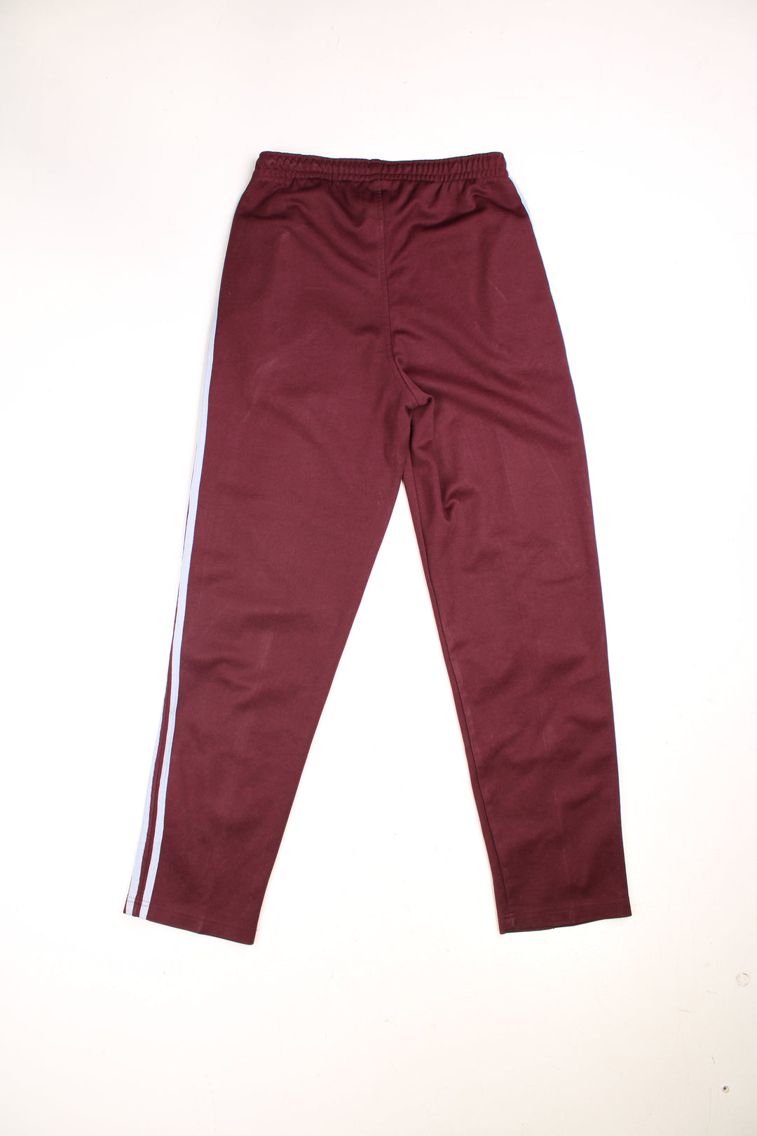  Tracksuit Bottoms in a burgundy  colourway with light blue stripes going down the sides, has an elasticated waist with drawstring, zip up side pockets, and the logo embroidered on the front. 