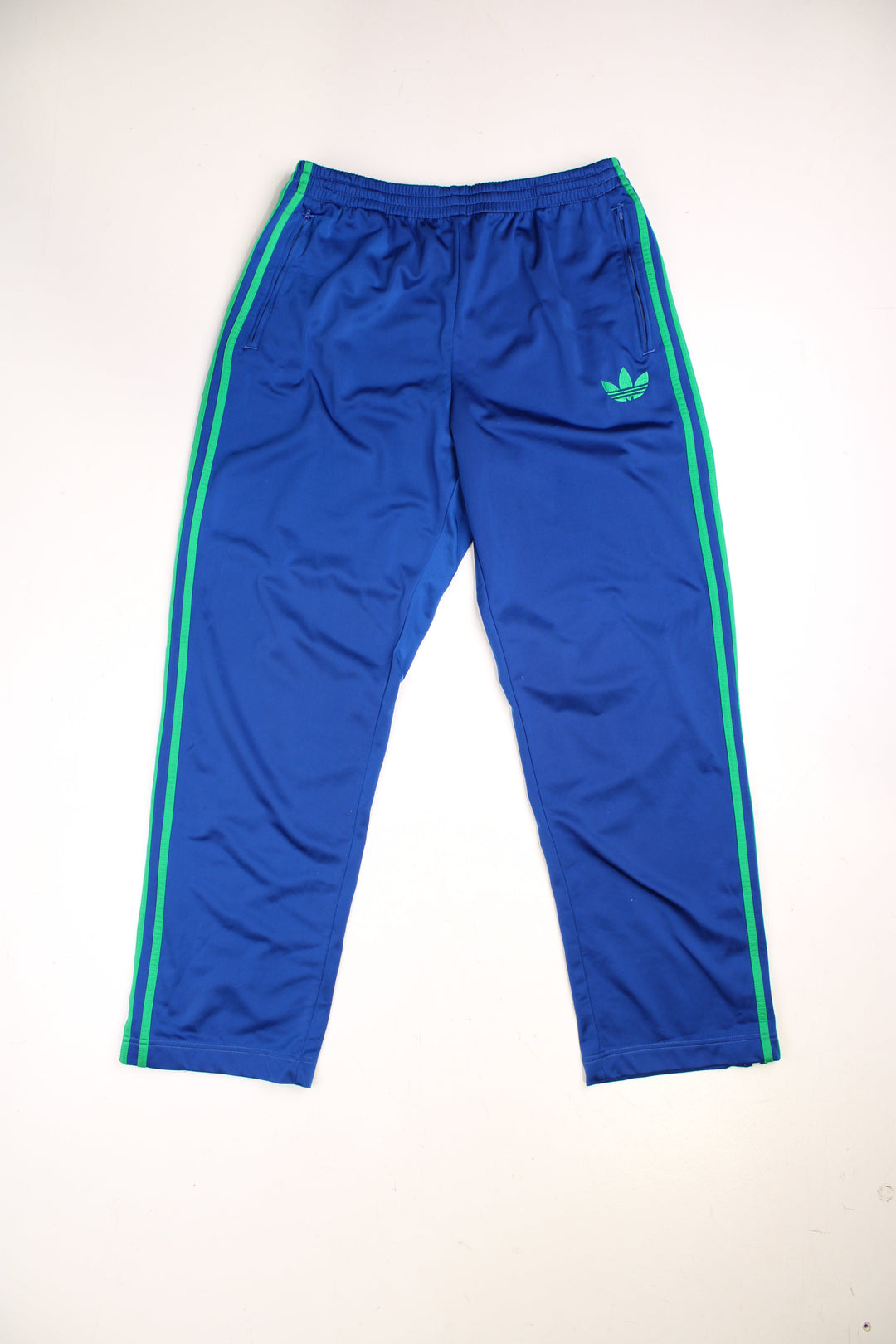 Adidas Tracksuit Bottoms in a blue colourway with the iconic three stripes going down the sides in green, has an elasticated waist with drawstring, side pockets, and the logo embroidered on the front. 