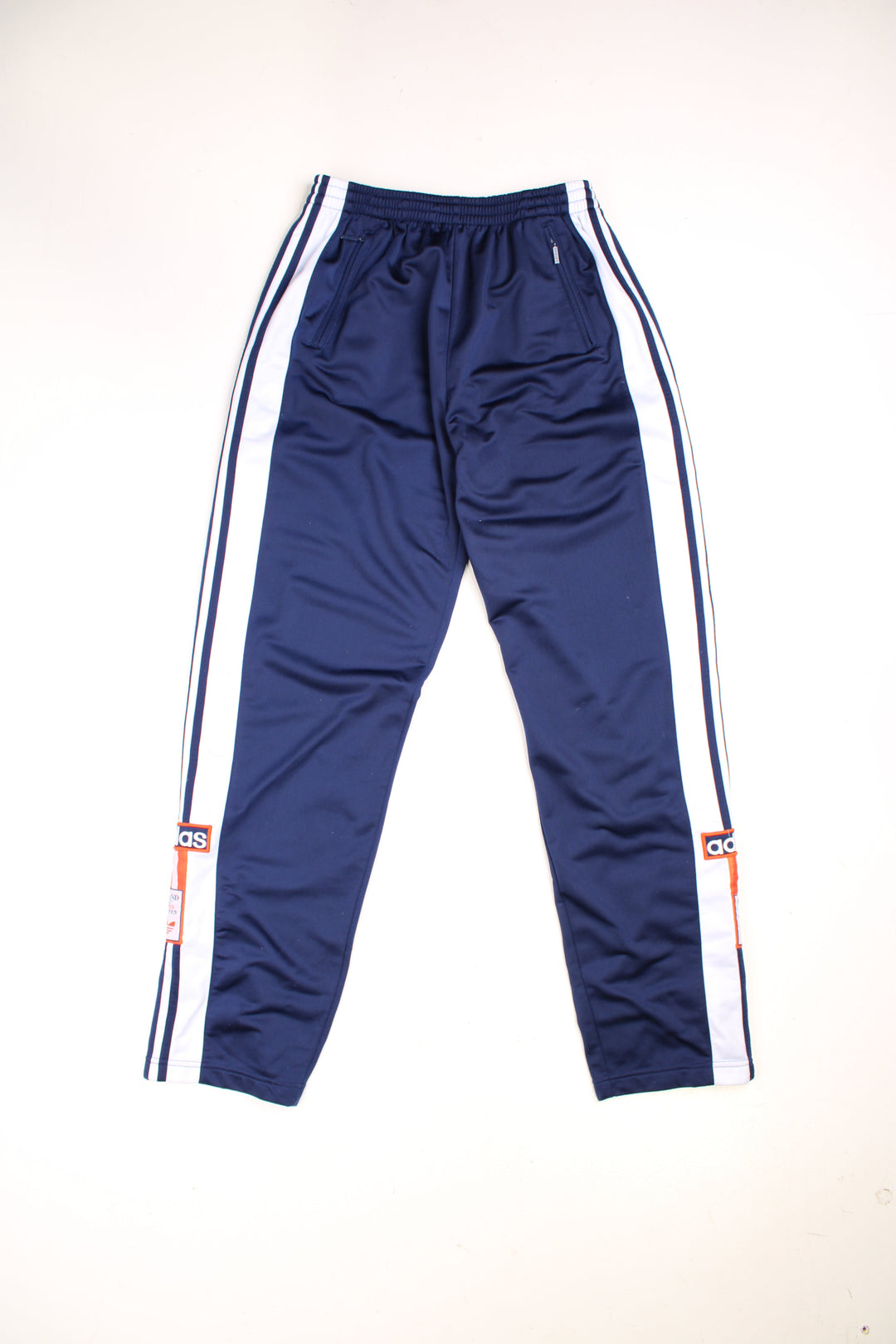 Vintage Adidas Popper Tracksuit Bottoms in a blue colourway with stripes going down the sides, has an elasticated waist with drawstring, zip up side pockets, and the logo embroidered on the down the legs. 