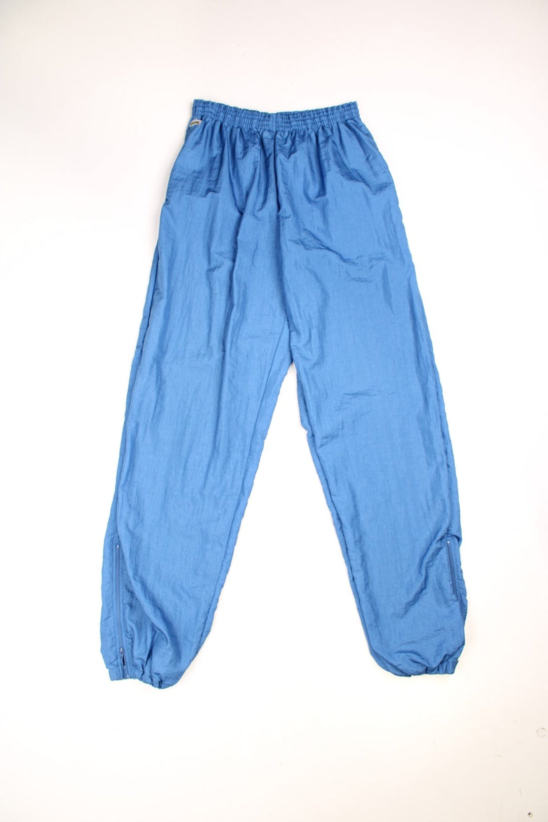 Vintage Chemise Lacoste Shell Tracksuit Bottoms in a blue colourway, side pockets, and has the logo embroidered on the front. 