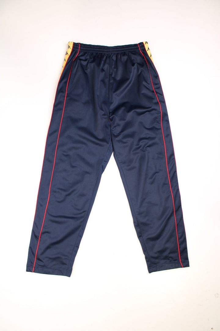 Vintage Kappa Tracksuit Bottoms in a blue colourway with orange and red stripes with the logo on going down the sides, has side pockets, and an elasticated waist with drawstring. 