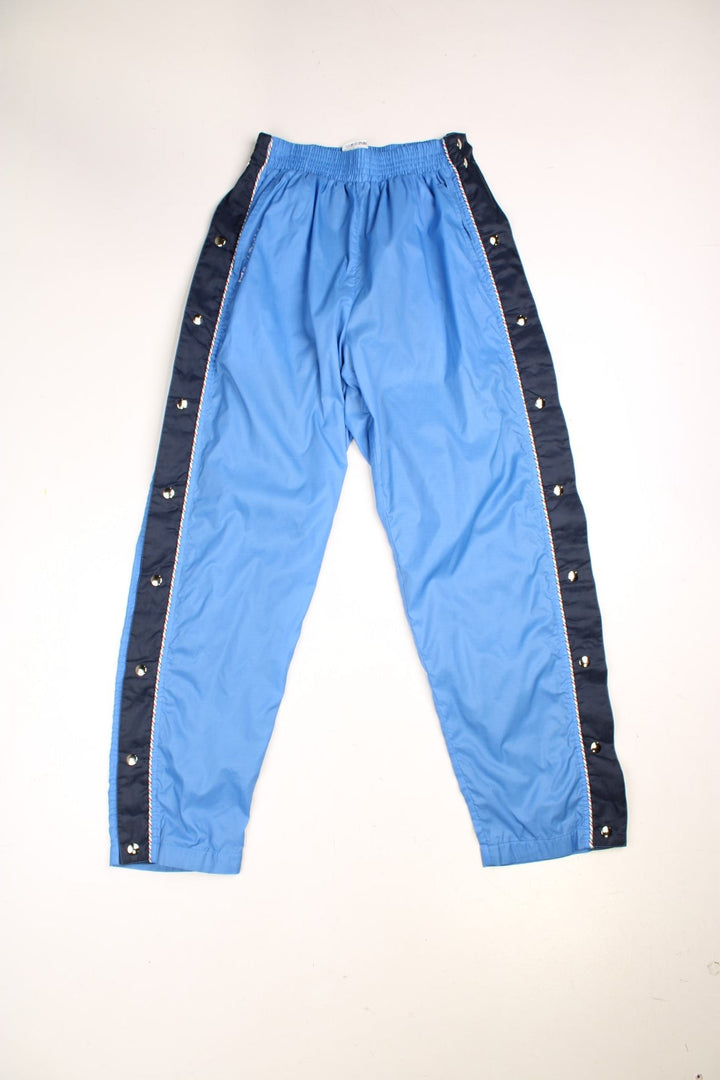 Vintage Sergio Tacchini Popper Tracksuit Bottoms in a blue colourway with stripes going down the sides, has side pockets, and an elasticated waist. 