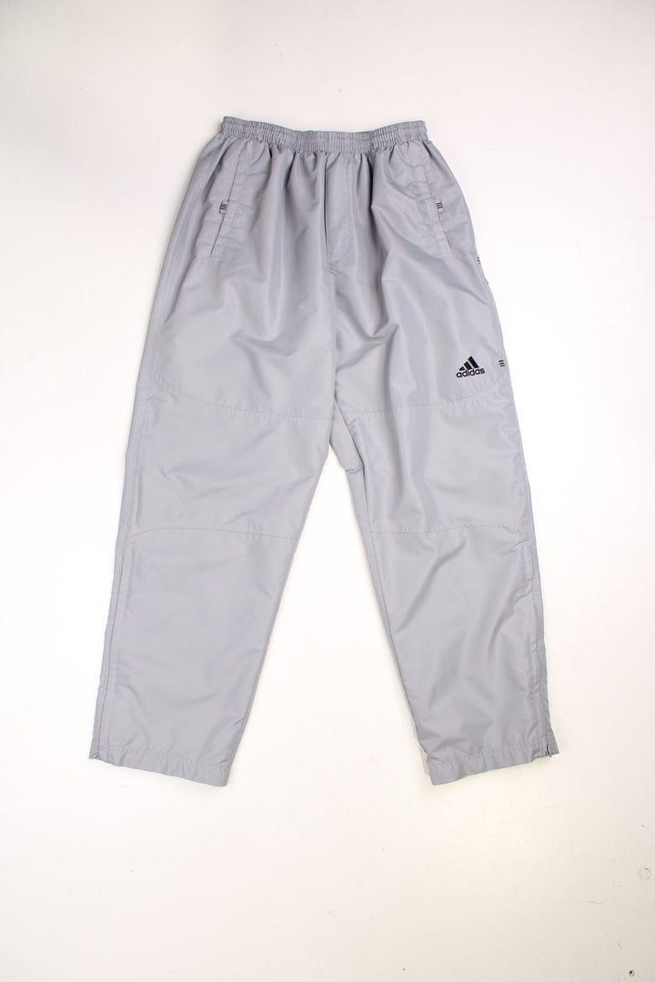 Adidas Tracksuit Bottoms in a grey colourway, has pockets, an elasticated waist with drawstring, mesh lining, and the logo embroidered on the front and on the back of the right leg. 