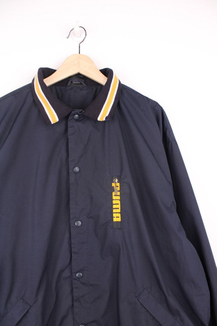 Puma King collared tracksuit jacket in blue and yellow. Features embroidered logo on the chest and sleeve, and multiple pockets.