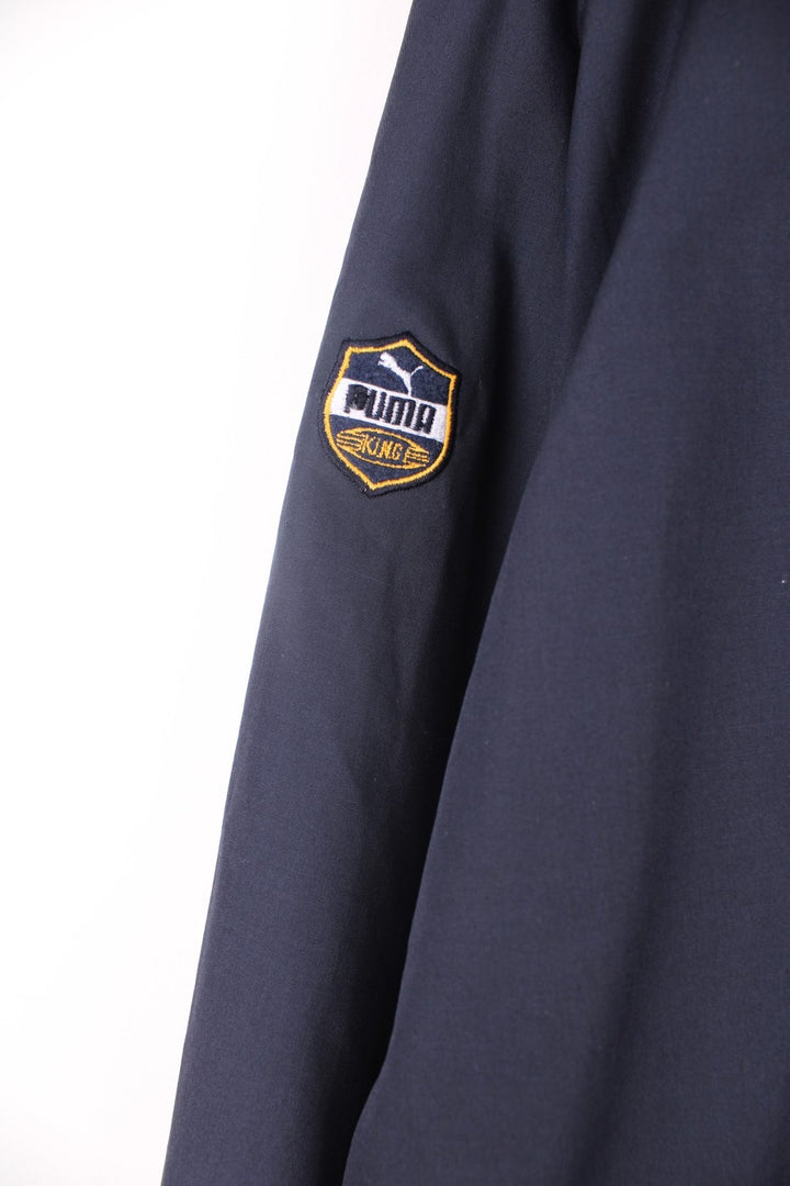 Puma King collared tracksuit jacket in blue and yellow. Features embroidered logo on the chest and sleeve, and multiple pockets.