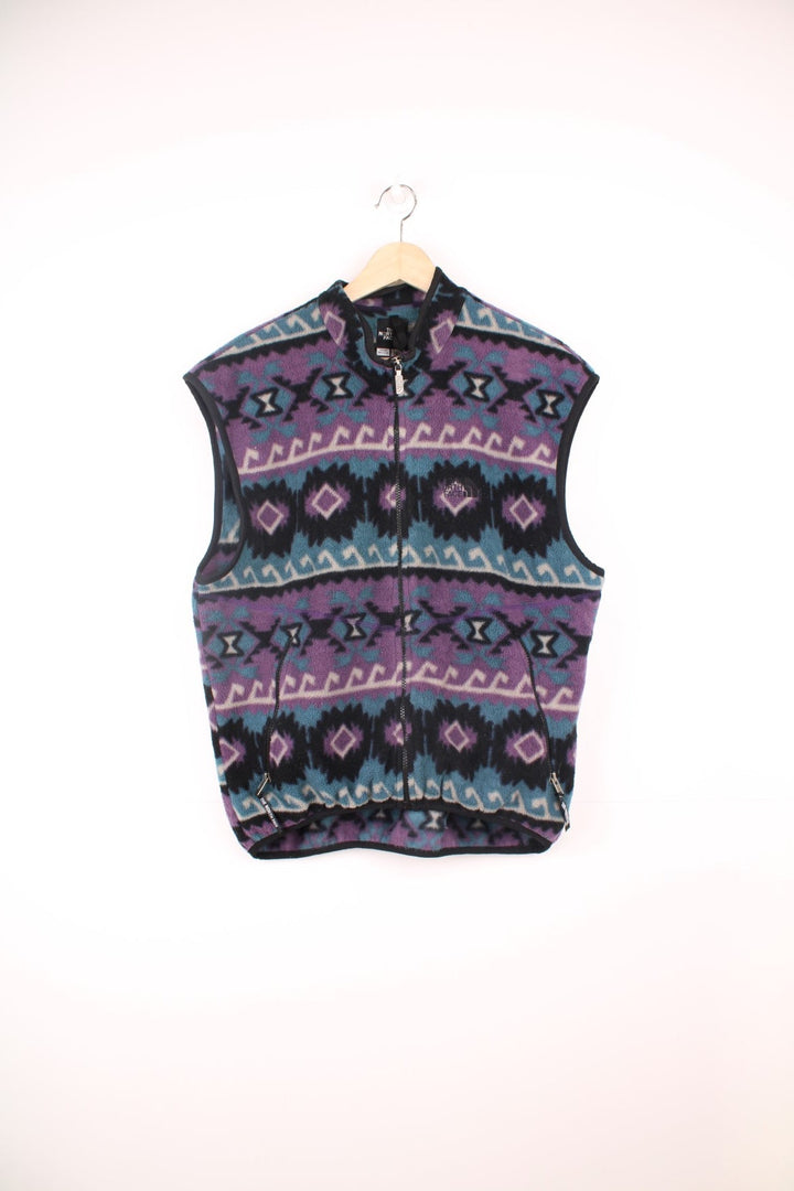 The North Face zip through fleece gilet in purple, blue and black aztec pattern. Features embroidered logo on the chest.