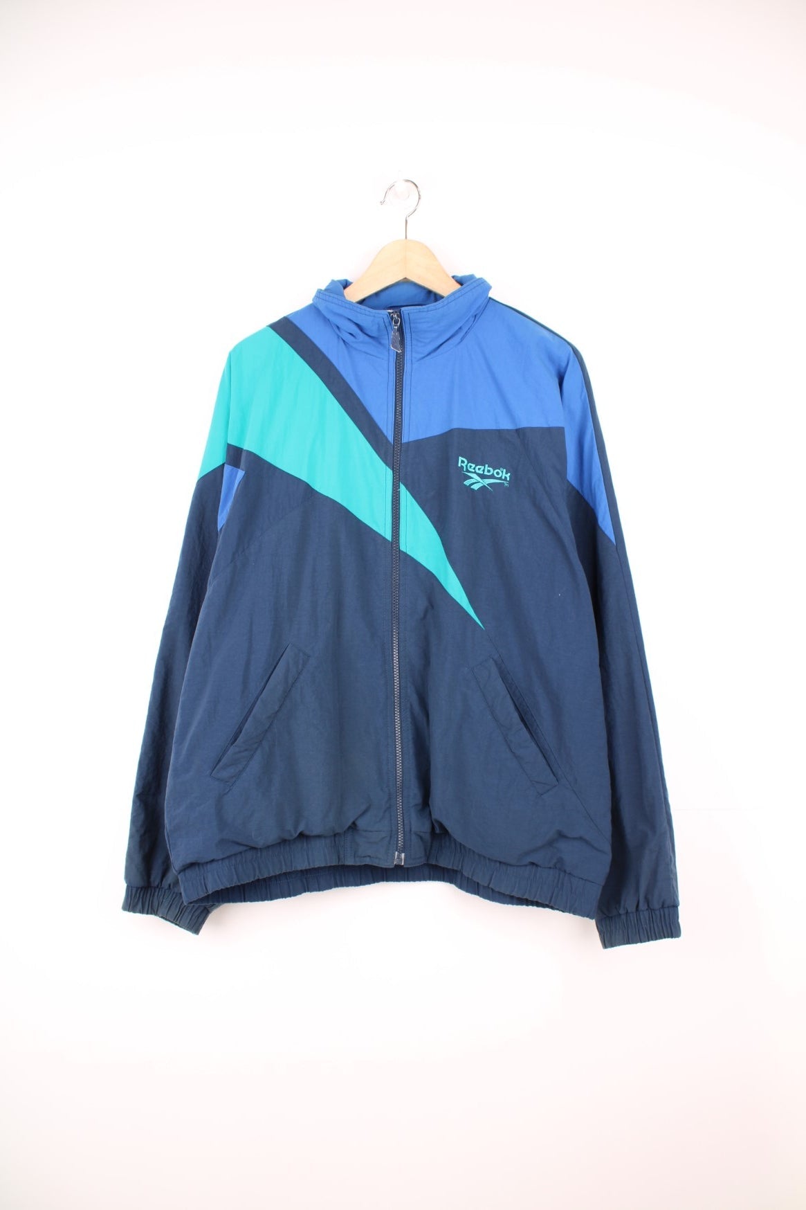 Vintage 90s Reebok zip through tracksuit top in blue and green. Features embroidered logo on the chest.