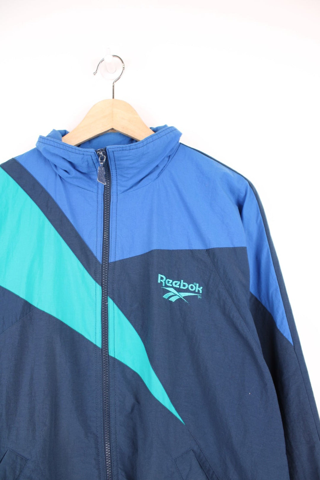 Vintage 90s Reebok zip through tracksuit top in blue and green. Features embroidered logo on the chest.