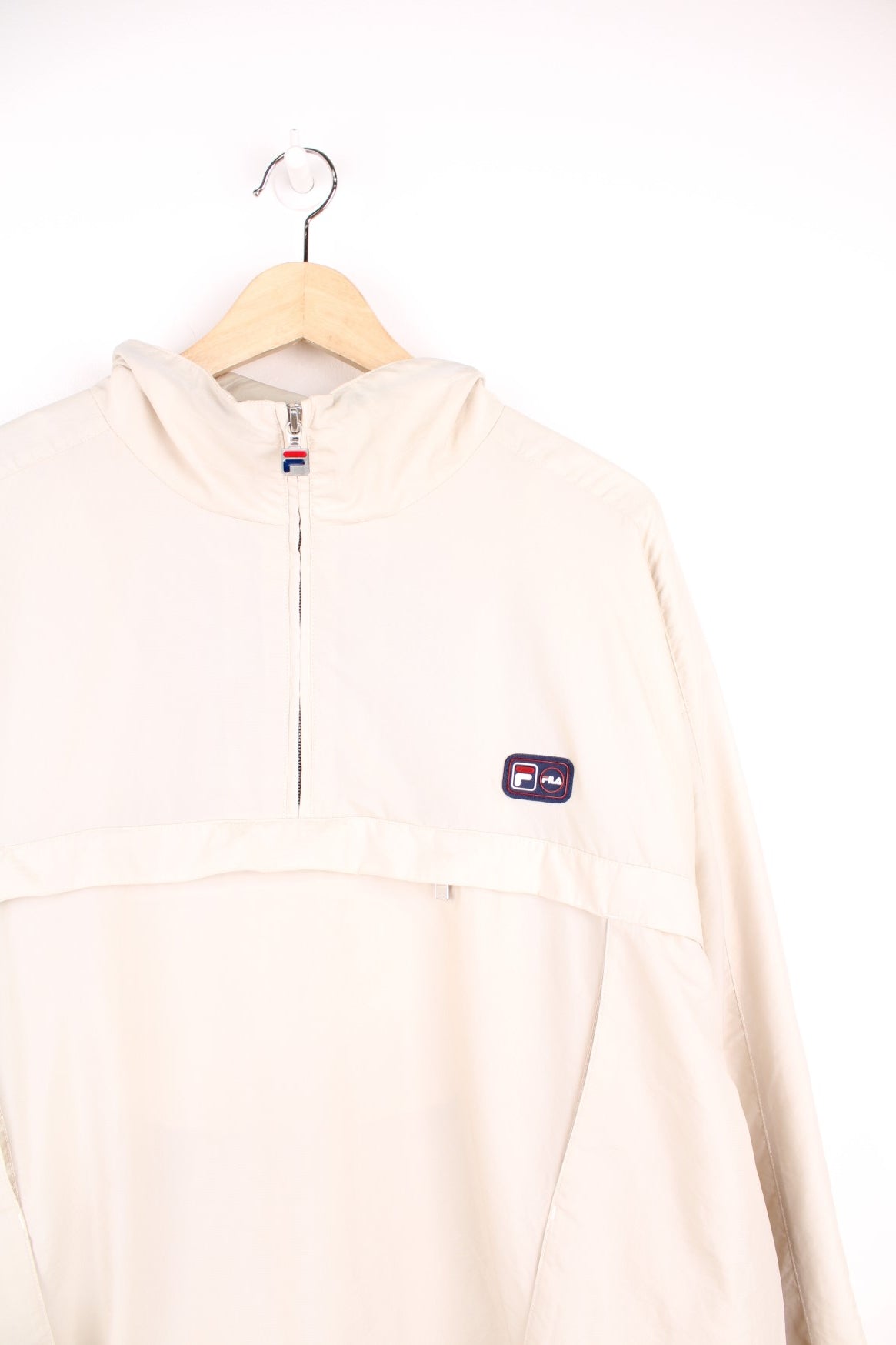 Fila quarter zip, hooded windbreaker jacket. Features puff print logo on the chest, pouch pocket, side pockets and velcro cuffs.