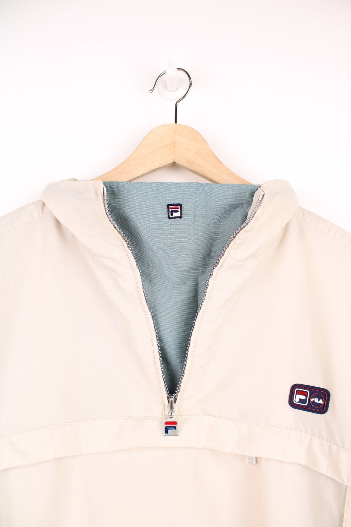 Fila quarter zip, hooded windbreaker jacket. Features puff print logo on the chest, pouch pocket, side pockets and velcro cuffs.