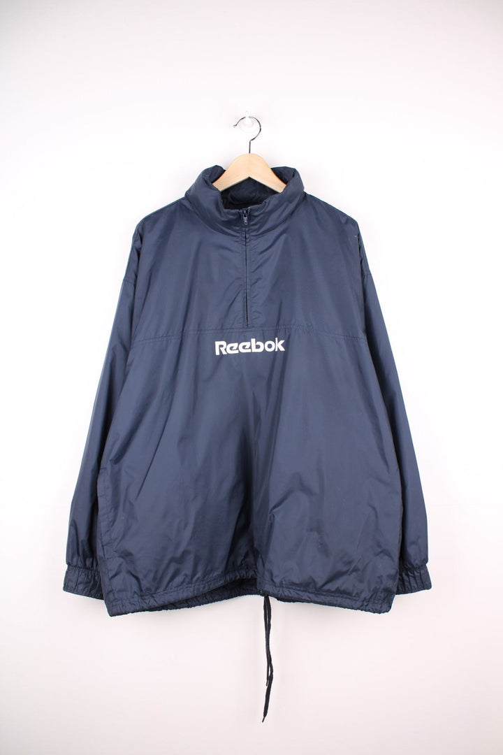 Reebok 1/2 zip shell jacket in navy blue with two pockets and drawstring waist adjustment. 