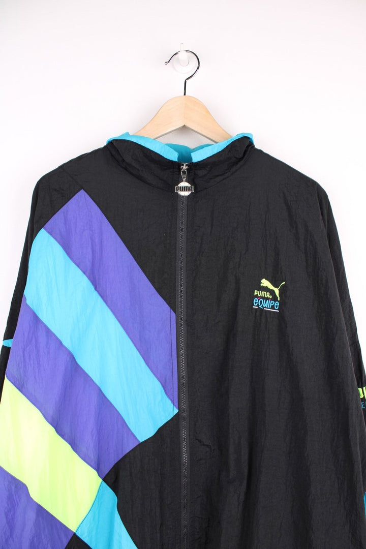 90s Puma Equipe track top/shell jacket in black with blue, green and purple accents, two pockets, zip closure and an embroidered logo.