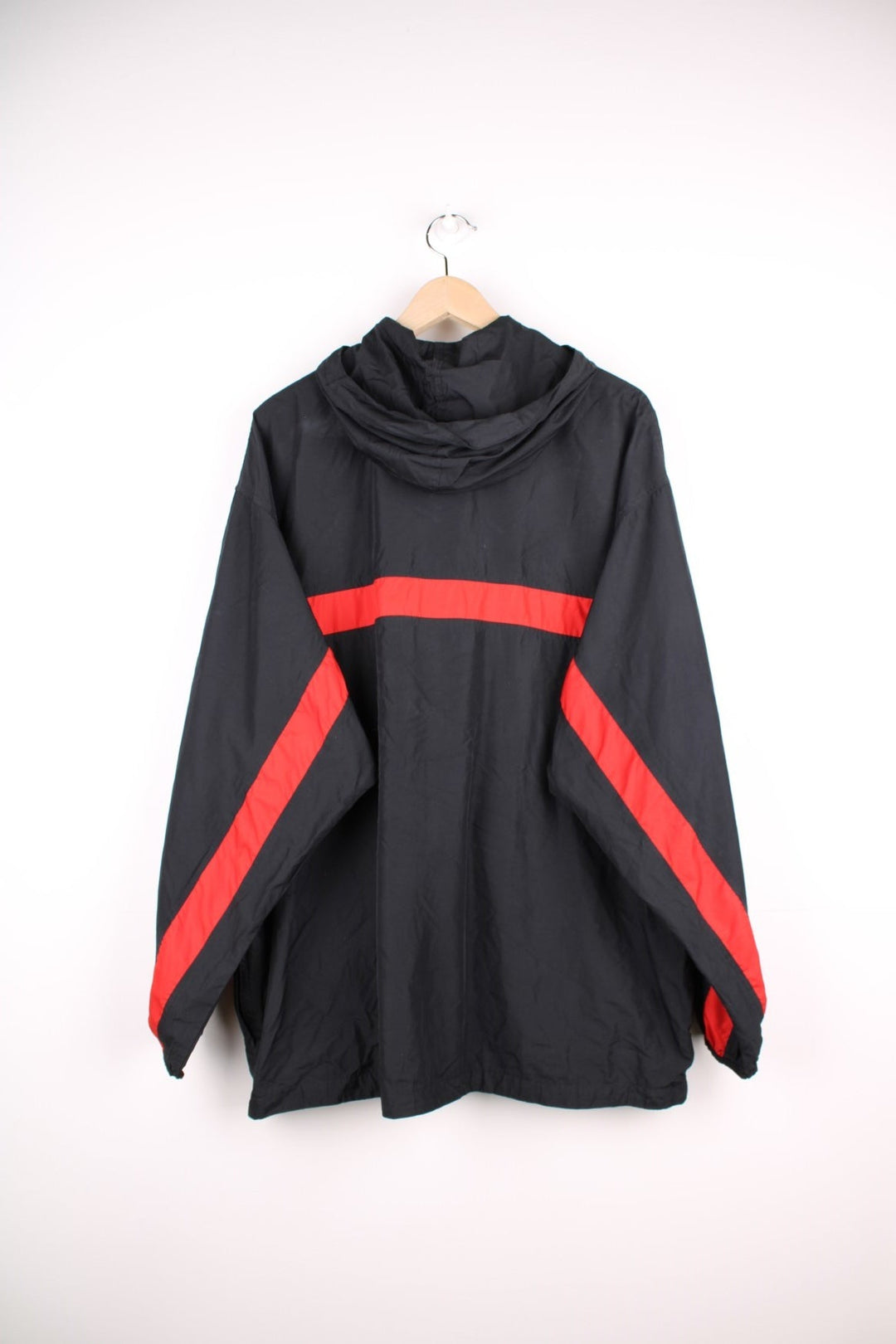 Nike ACG 1/2 zip hooded lightweight windbreaker in black with a central red stripe detail, three zipped pockets, mesh lining, an embroidered ACG logo, and toggle adjusters at the collar. 