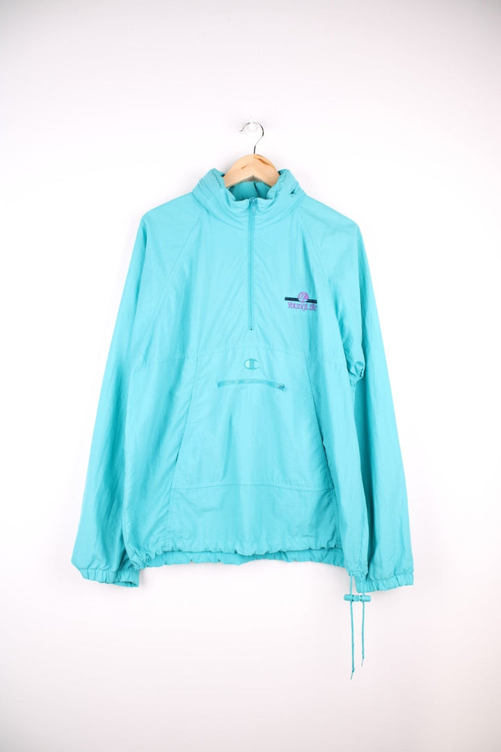 Vintage Champion Pullover Windbreaker in a light blue colourway, zips up half way and has pouch pockets, hidden hood, and the logo embroidered on the front as well as 'Young Life' company spell out on the chest.