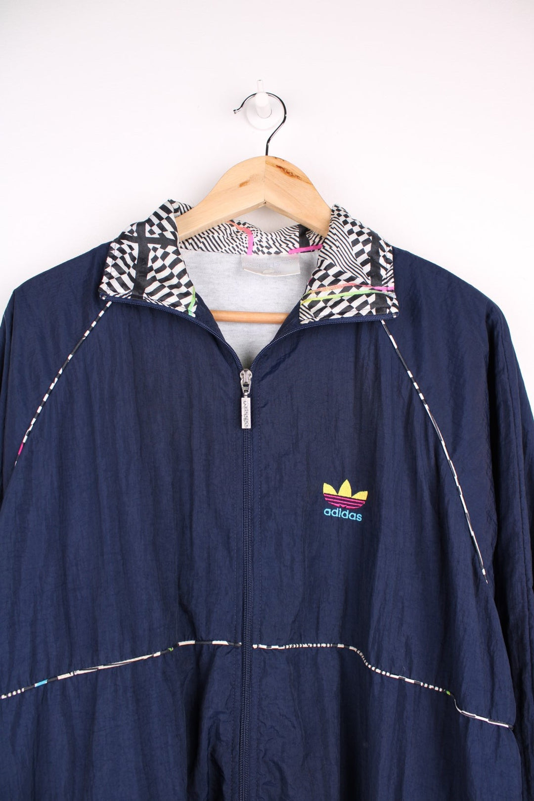  Tracksuit Jacket in a navy  colourway with patterned stripes going around the sides, zip up closure and has side pockets, cotton lining, and the logo embroidered on the front.