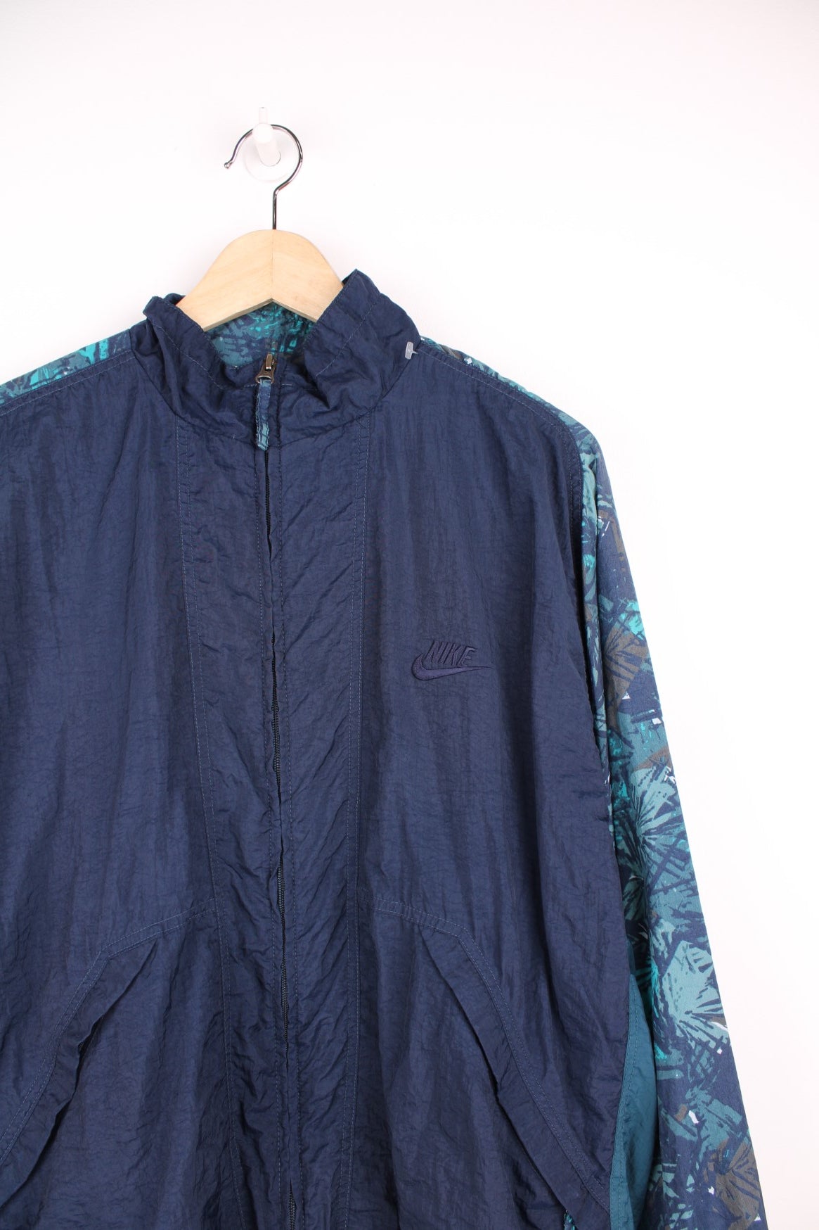 Vintage 90s Nike tracksuit top in blue with embroidered logo on the chest and patterned sleeves.