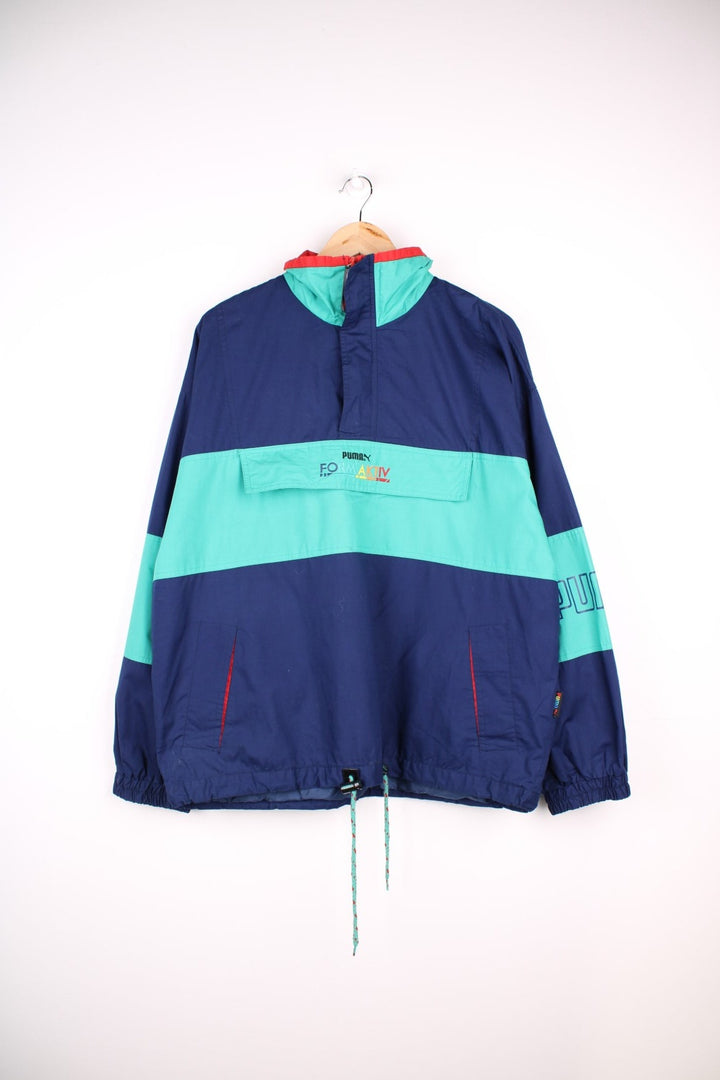 Vintage Puma Formaktiv Pullover Windbreaker in a navy blue and green colourway, half zip up closure, multiple pockets, and has the spell out logo embroidered across the front and printed on the left sleeve.