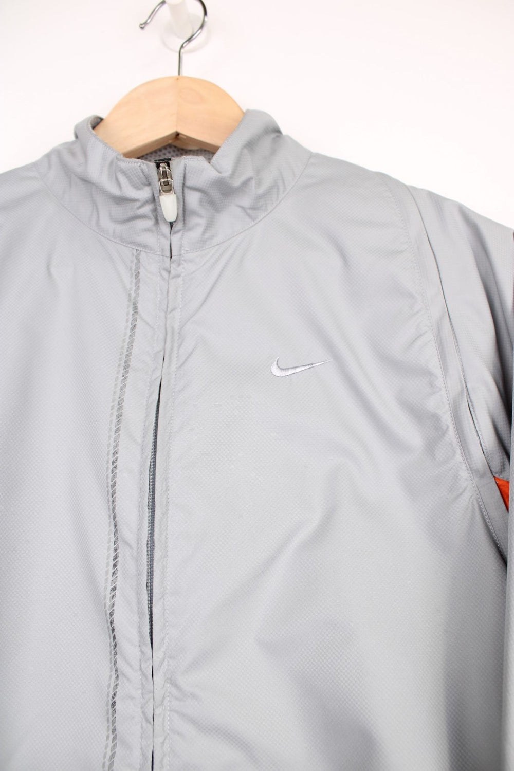 Nike Clima Fit grey zip through lightweight track jacket, with removable zip off sleeves, drawstring waist and high-vis orange detailing 