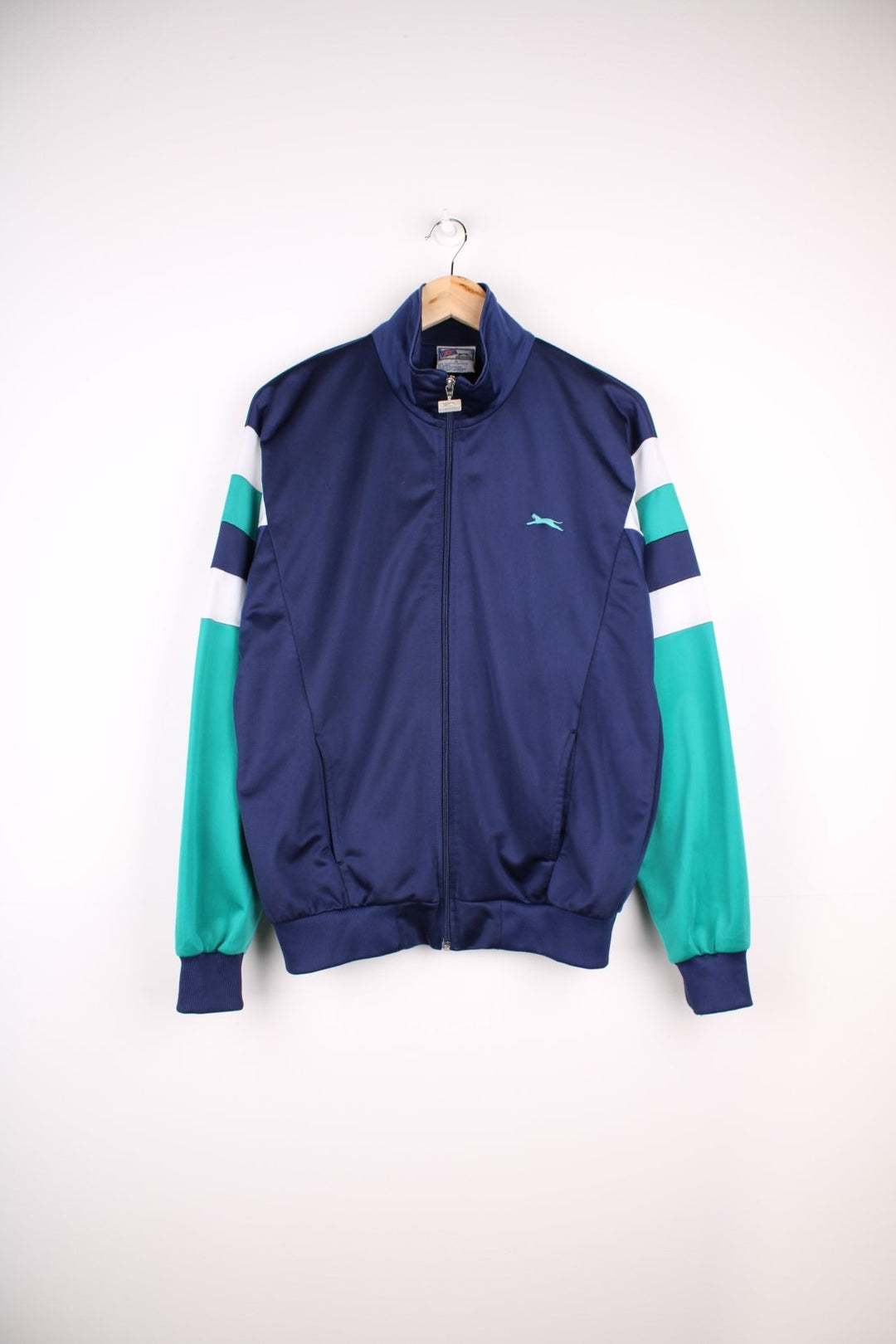 Vintage Slazenger Tracksuit Top in a blue, green and white patterned colourway, zip up closure and has side pockets, and the logo embroidered on the front.