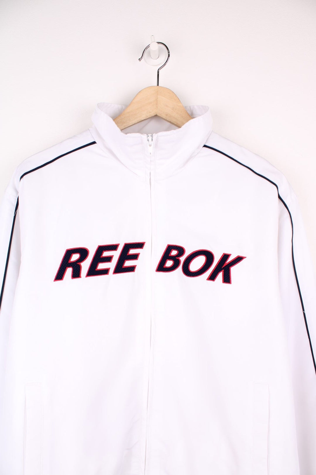 White Reebok tracksuit top with embroidered spell out logo across the chest.