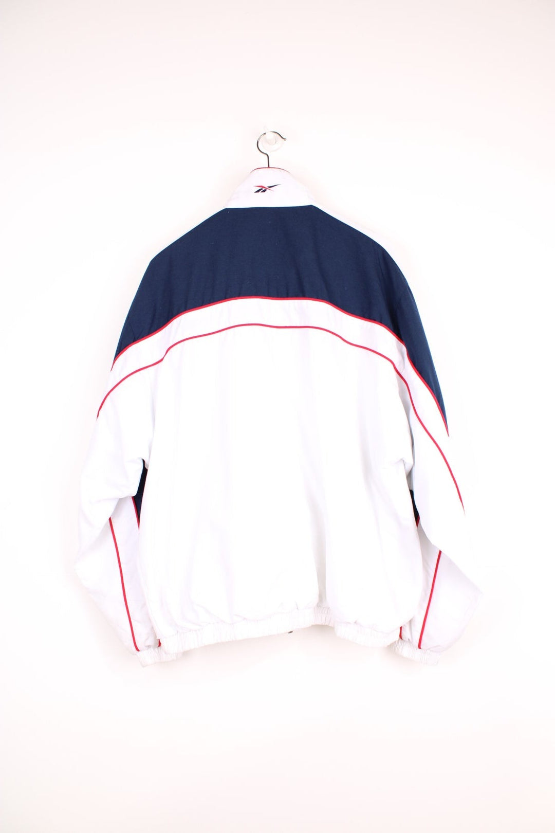 Reebok all white zip through tracksuit top, features embroidered logo on the chest and cuff ,navy blue panels and red piping. 