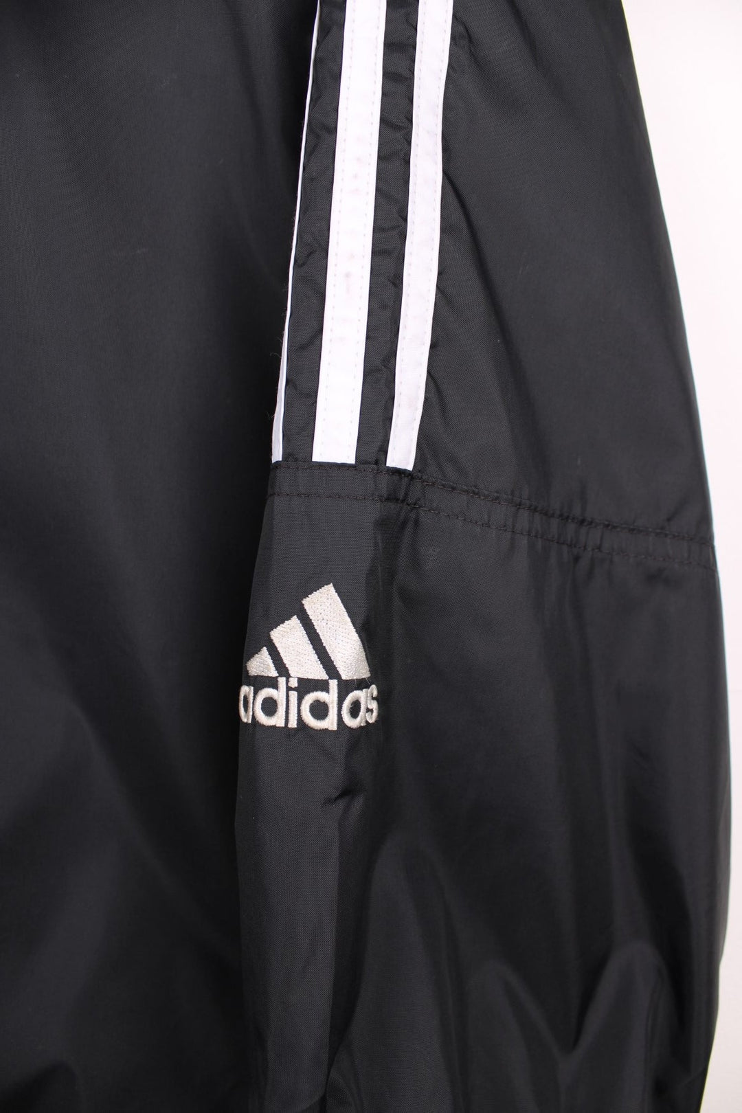  Windbreaker in a  colourway with the iconic three stripes going down the sleeves, zip up closure, has multiple pockets, hidden hood, and the logo embroidered on the front and larger on the back.