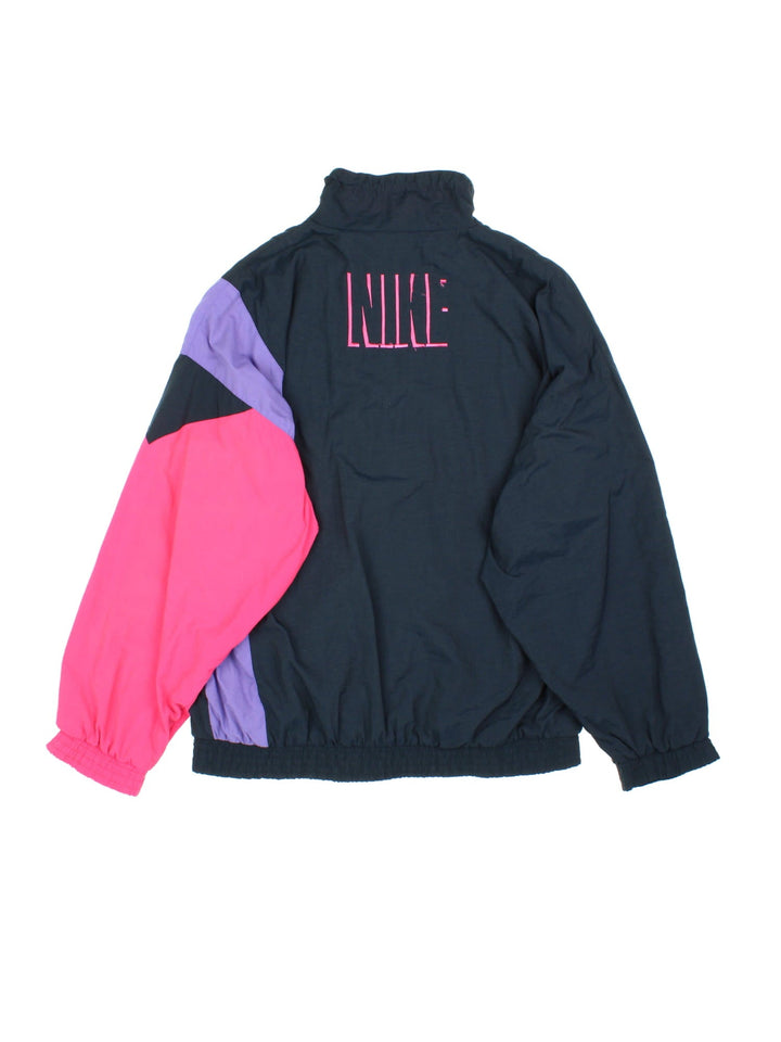 Vintage 90's Nike Windbreaker Jacket in a black, purple and pink patterened colourway. Zips up and has side pockets, and the logo embroidered on the front.