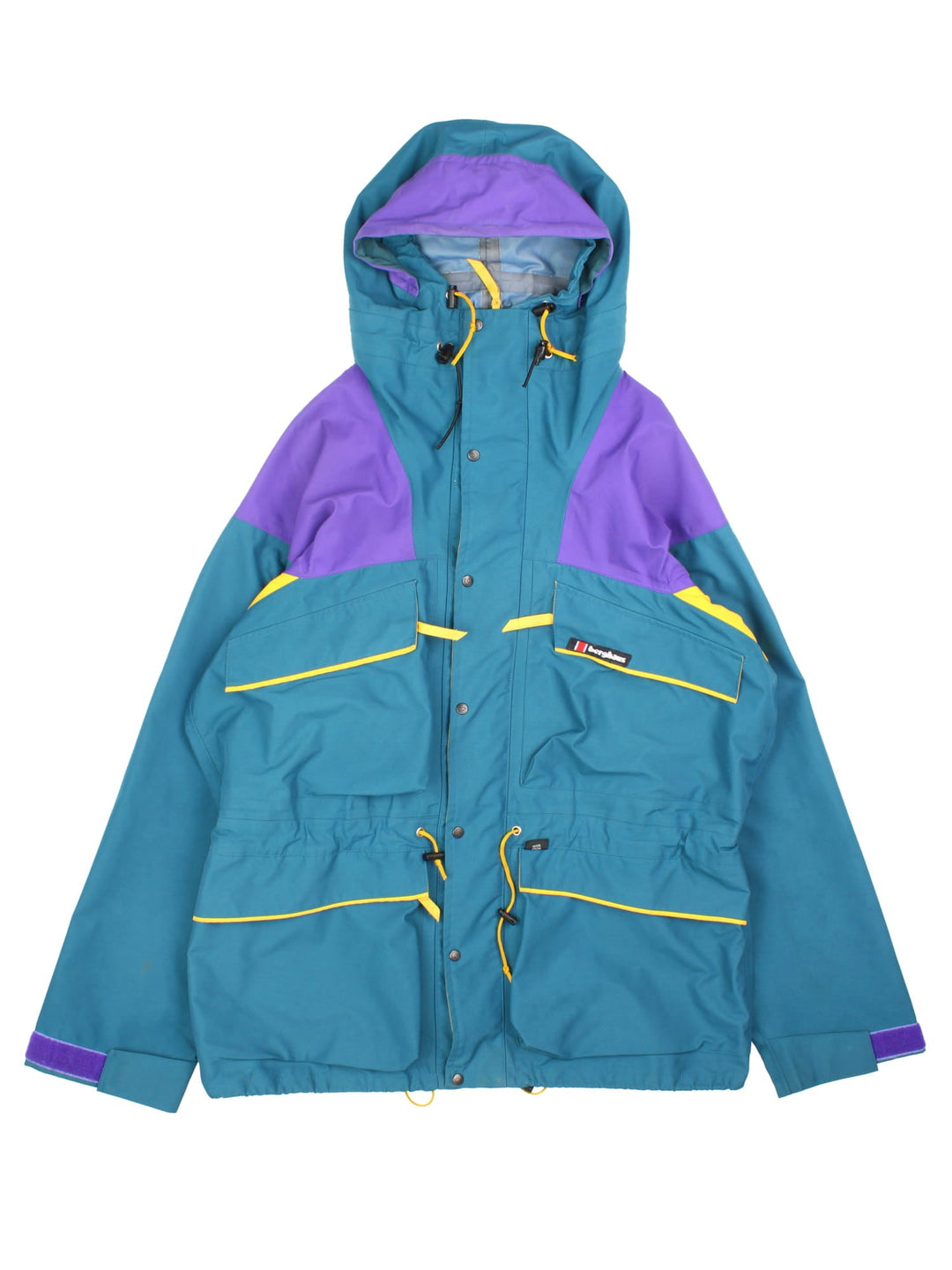 Vintage Berghaus Trango Jacket in a blue, purple and yellow colourway. Zips and buttons up, has multiple pockets, hooded, and the logo embroidered on the front.