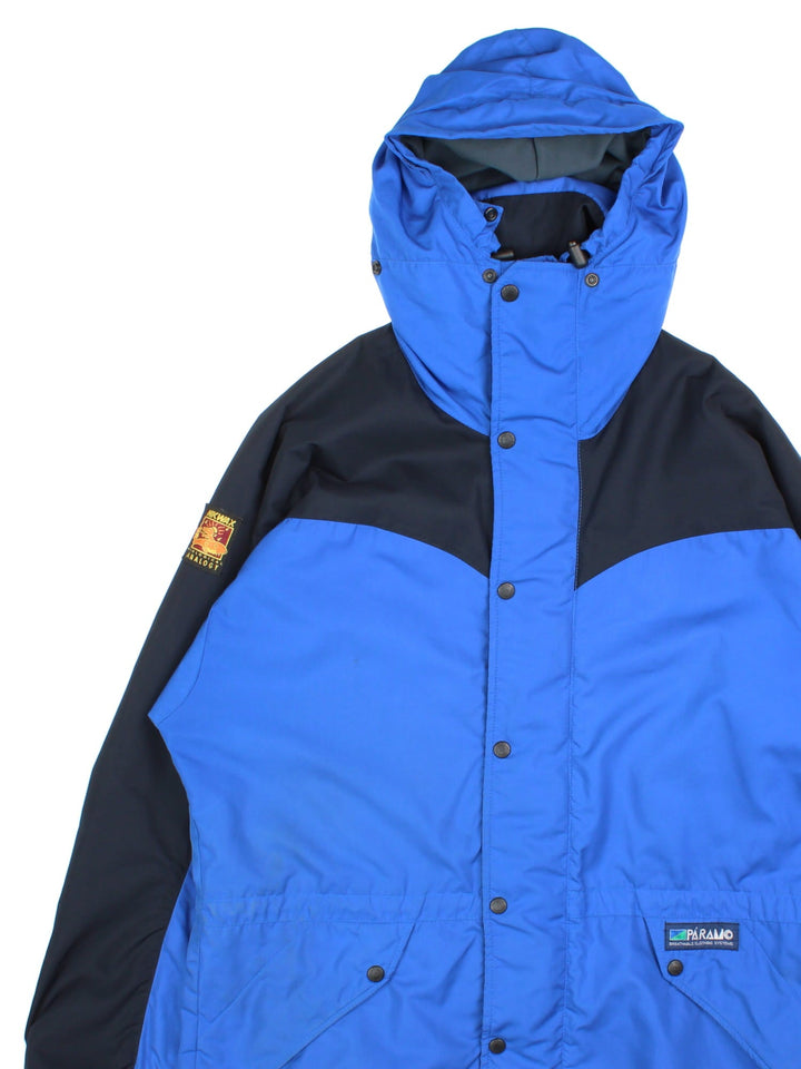 Vintage Paramo Nikwax Jacket in a blue and black colourway. Zips and buttons up, has side pockets, insulated lining, hooded, and has the logo embroidered on the front amd on the right sleeve.