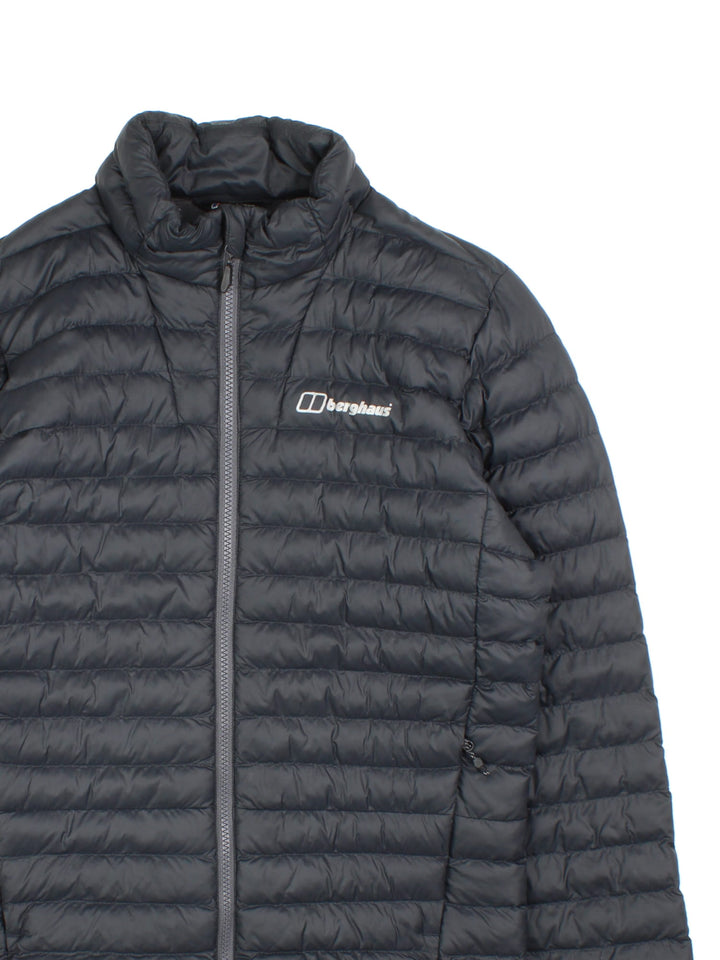 Berghaus Puffer Coat in a black colourway. Zips up and has side pockets, insulated lining, and has the logo printed on the front.