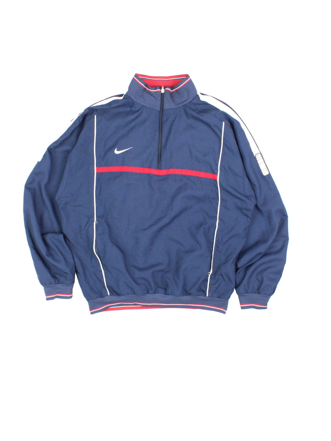 Vintage Nike 1/4 zip reversible pullover track top in navy blue with two zipped pockets, red and white stripe detailing, and a logo on the sleeve. Reverse side is red with blue and white stripe detailing. Swoosh embroidered on the chest of both sides.