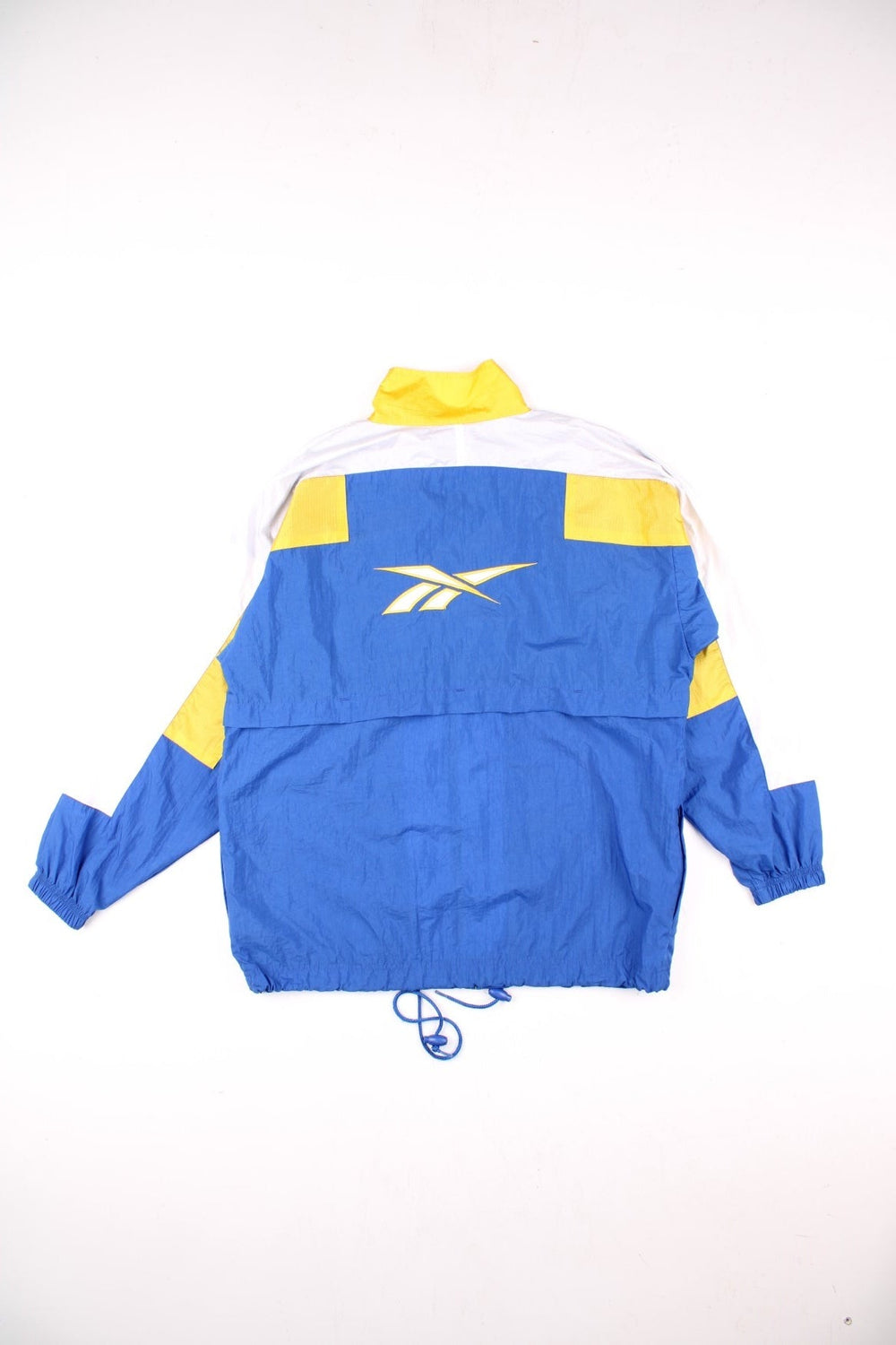 Vintage 90's Reebok Windbreaker Jacket in blue, with yellow and white panelling, two pockets, zip and velcro closure, a drawstring at the hem, and an embroidered logo on the chest and back.