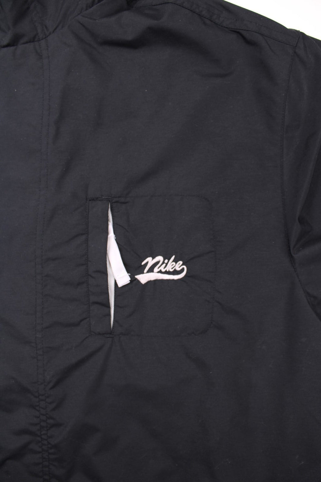 Vintage 90's Nike windbreaker in black, with three pockets, zip closure, and an embroidered logo on the chest.