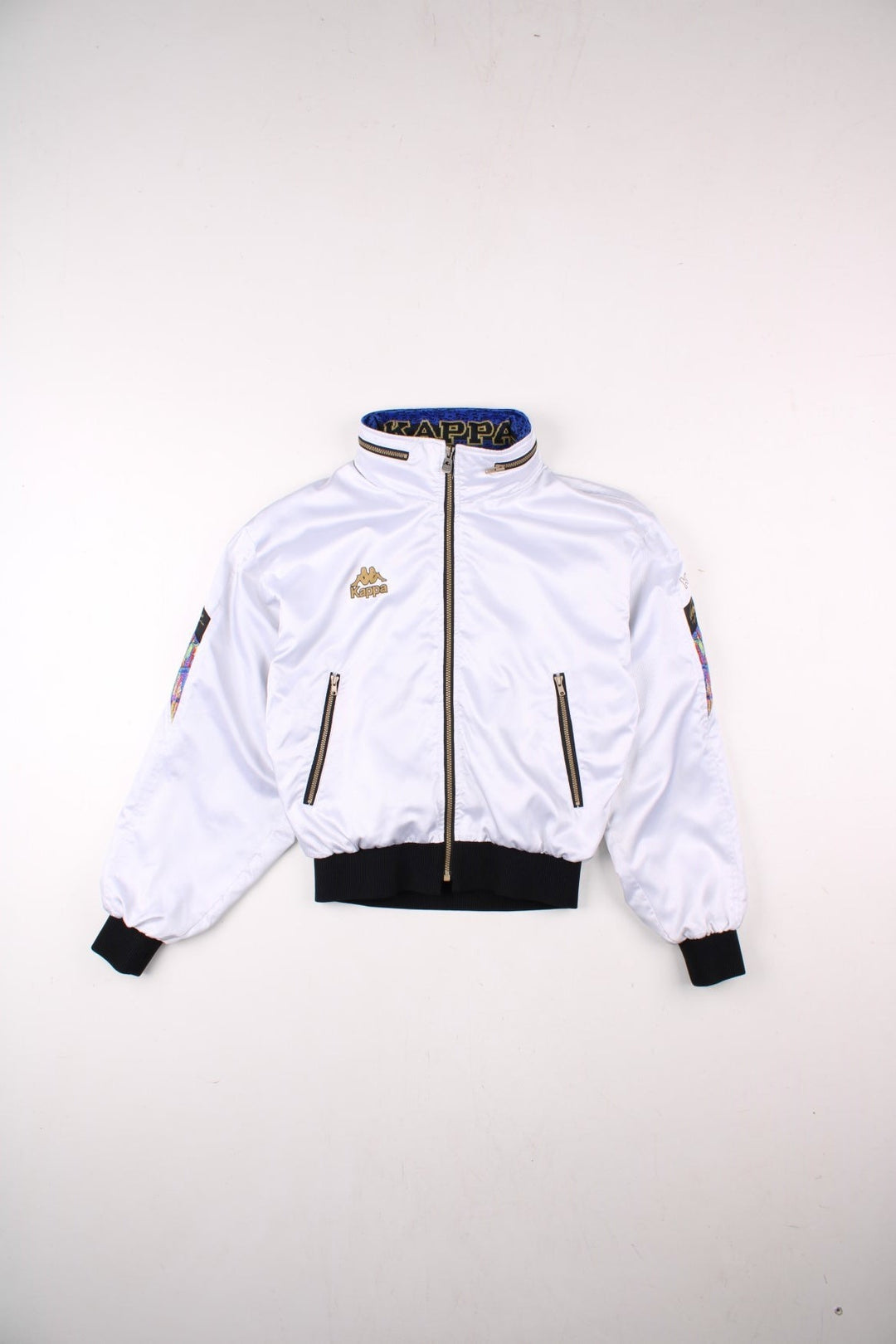 Vintage Kappa Lightweight Bomber Jacket in white, with black hem and cuffs, colourful patches on each sleeve, two pockets, hidden hood, zip closure, and a printed logo on the chest.