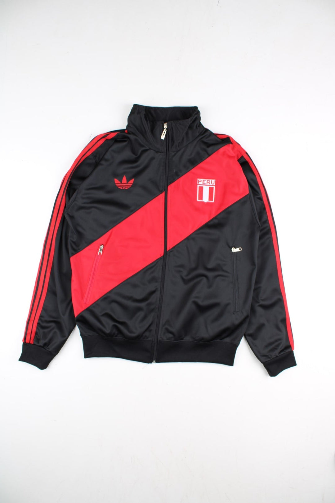 Adidas Rare Peru Track Top in a black colourway with classic red 3 stripe and red panelling. Small adidas logo and Peru badge on the front, with Peru lettering on the back. Full zip and double pockets.