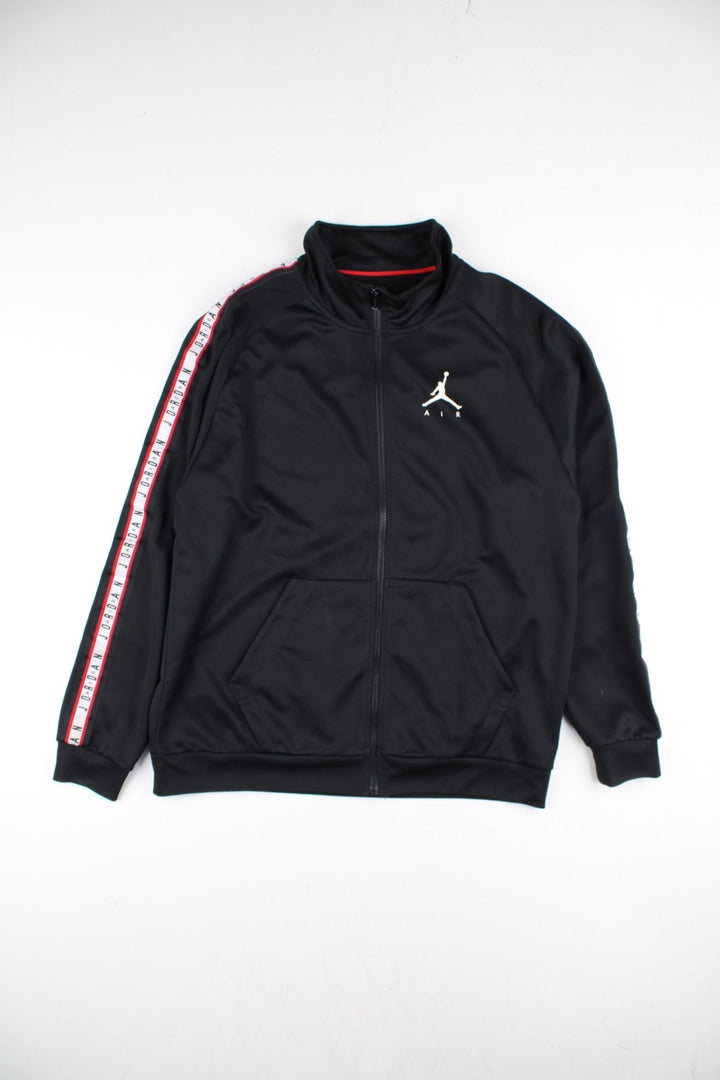 Vintage Air Jordan Track Top in a black colourway with Air Jordan stripe down the sleeves and classic logo on the front. Full zip with double front pocket.