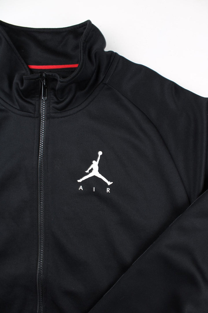 Vintage Air Jordan Track Top in a black colourway with Air Jordan stripe down the sleeves and classic logo on the front. Full zip with double front pocket.