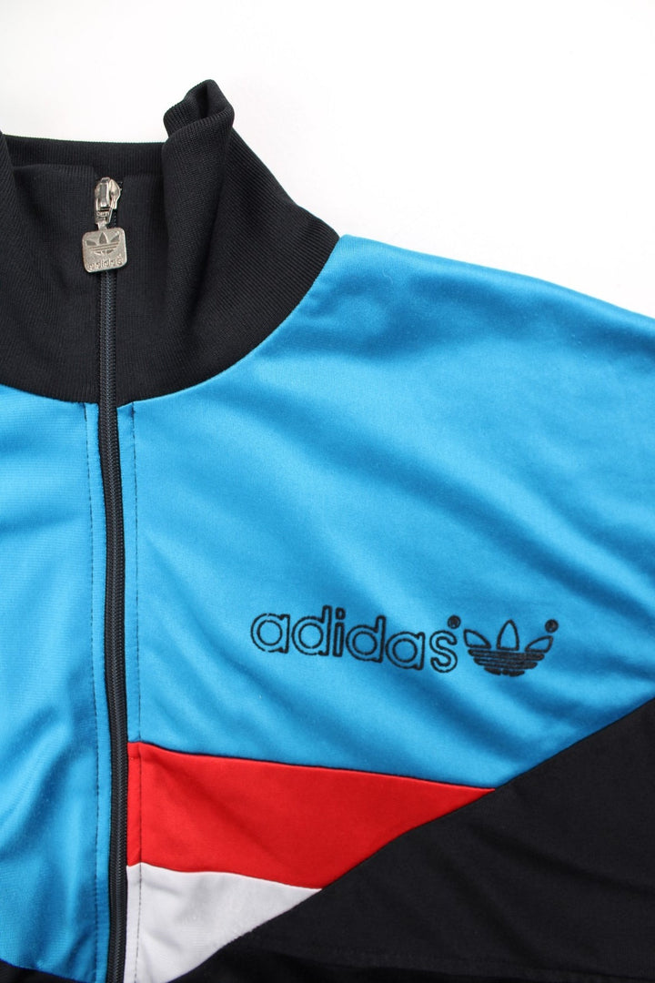 Vintage Adidas Track Top in a black colourway with blue top half panelling and small classic logo on the front with a full zip